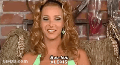 A Woman Is Sitting In A Chair And Smiling While Wearing A Green Top And Earrings . GIF