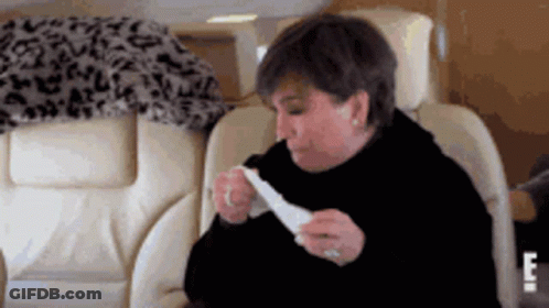 A Woman Is Sitting In A Chair Eating A Piece Of Food . GIF