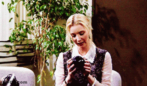A Woman Is Sitting In A Chair Holding A Black Object GIF