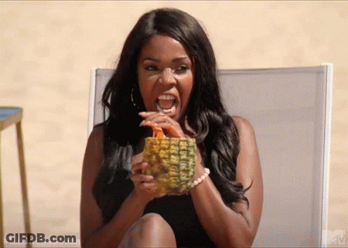 A Woman Is Sitting In A Chair Holding A Pineapple And Drinking From It . GIF