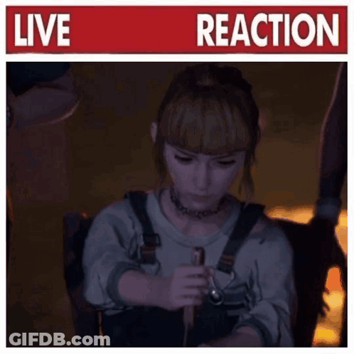 A Woman Is Sitting In A Chair Holding A Stick In Front Of A Sign That Says Live Reaction GIF