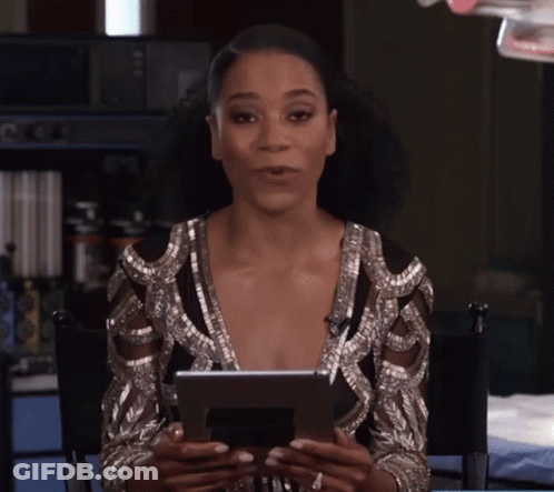 A Woman Is Sitting In A Chair Holding A Tablet In Her Hands GIF