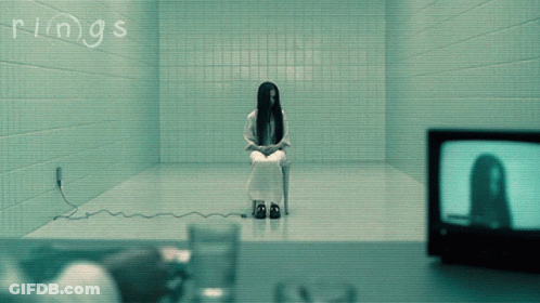 A Woman Is Sitting In A Chair In A Room With The Word Rings Written On The Wall GIF