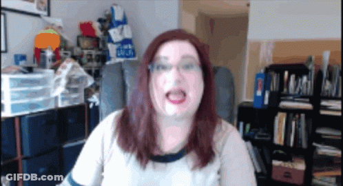A Woman Is Sitting In A Chair In Front Of A Bookshelf With A Blue Bag That Says ' Blue ' On It GIF