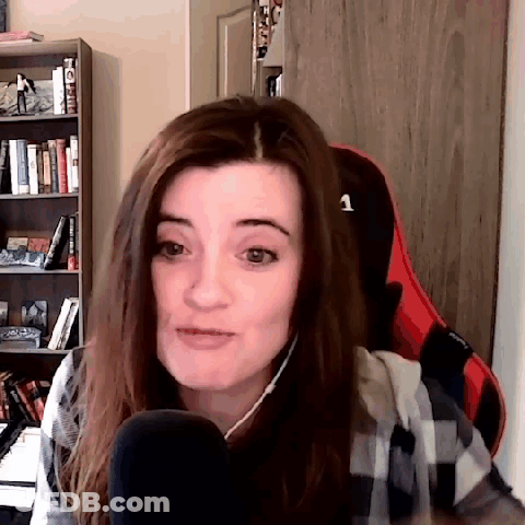 A Woman Is Sitting In A Chair In Front Of A Microphone And A Bookshelf . GIF