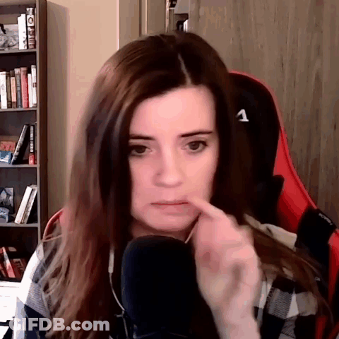 A Woman Is Sitting In A Chair In Front Of A Microphone And Making A Funny Face . GIF
