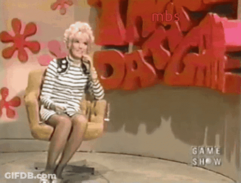 A Woman Is Sitting In A Chair In Front Of A Wall That Says Mbs GIF