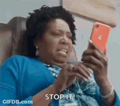 A Woman Is Sitting In A Chair Looking At Her Cell Phone And Making A Funny Face . GIF