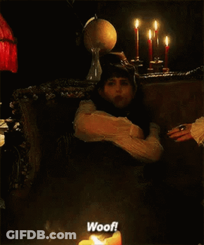 A Woman Is Sitting In A Chair Next To A Lit Candle And Says Woof GIF