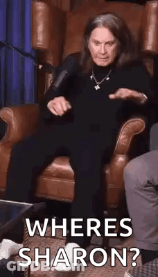 A Woman Is Sitting In A Chair With A Microphone And Asking Where Is Sharon ? GIF