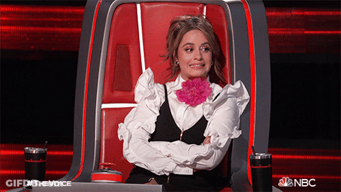 A Woman Is Sitting In A Chair With Her Arms Crossed And A Flower In Her Mouth .. GIF
