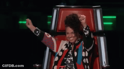A Woman Is Sitting In A Chair With Her Arms In The Air And Smiling . GIF