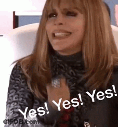A Woman Is Sitting In A Chair With Her Hands Folded In Front Of Her Chest And Smiling . GIF