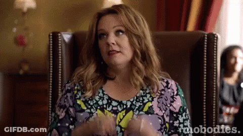 A Woman Is Sitting In A Chair With Her Hands In Her Pockets And Making A Funny Face . GIF