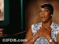 A Woman Is Sitting In A Chair With Her Hands On Her Heart . GIF