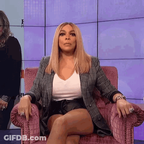 A Woman Is Sitting In A Chair With Her Legs Crossed And A Serious Look On Her Face . GIF