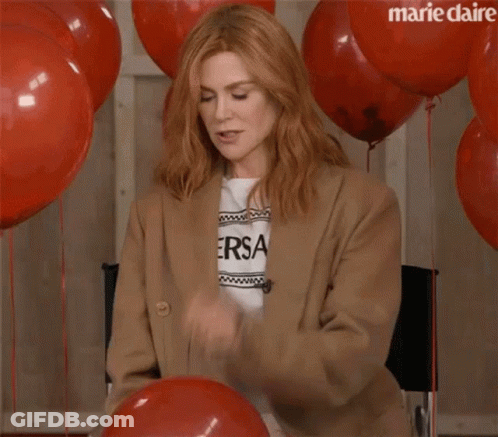 A Woman Is Sitting In A Chair With Red Balloons And Confetti Falling On Her . GIF