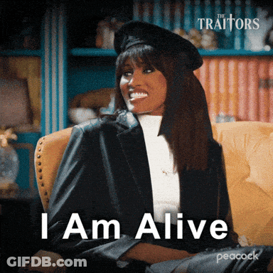 A Woman Is Sitting In A Chair With The Words " I Am Alive " On The Screen GIF