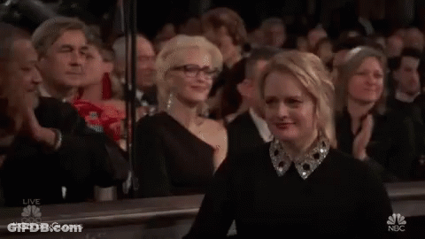 A Woman Is Sitting In A Crowd Of People Applauding At A Awards Ceremony . GIF