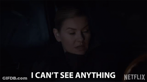 A Woman Is Sitting In A Dark Room And Says `` I Can T See Anything '' . GIF