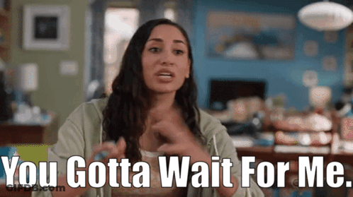 A Woman Is Sitting In A Living Room And Saying " You Gotta Wait For Me " GIF