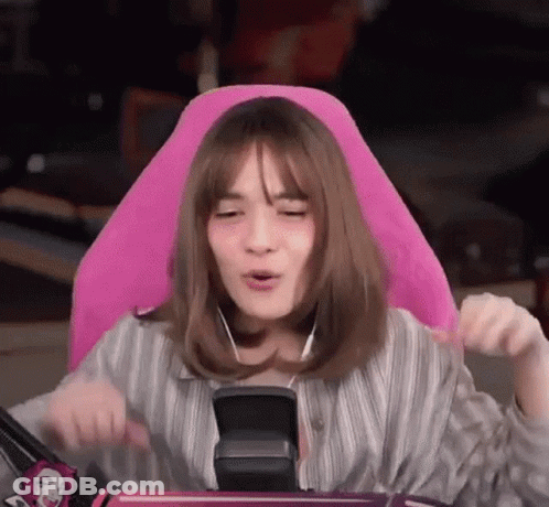 A Woman Is Sitting In A Pink Chair With Headphones On Her Ears . GIF