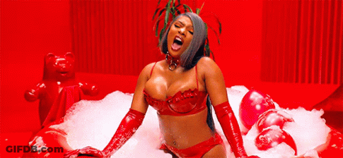 A Woman Is Sitting In A Red Bathtub Filled With Foam . GIF