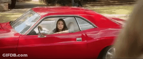 A Woman Is Sitting In A Red Car With Her Head Out The Window . GIF