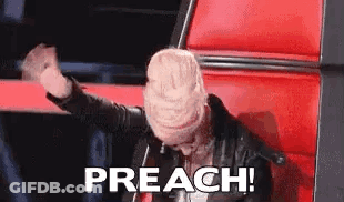 A Woman Is Sitting In A Red Chair With Her Hands In The Air And The Words `` Preach '' Written On The Screen . GIF