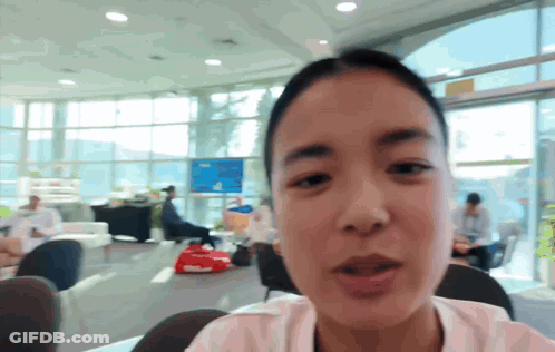 A Woman Is Sitting In A Room With A Lot Of Windows GIF