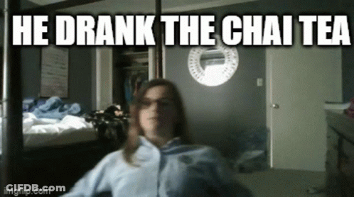 A Woman Is Sitting In A Room With The Words He Drank The Chai Tea Written Above Her GIF