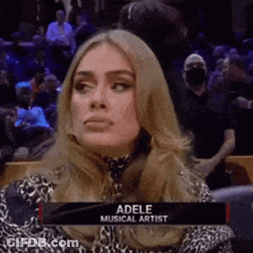 A Woman Is Sitting In A Stadium With A Sign That Says Adele Musical Artist On It . GIF