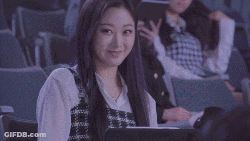 A Woman Is Sitting In A Theater With A Tablet In Her Lap And Smiling . GIF