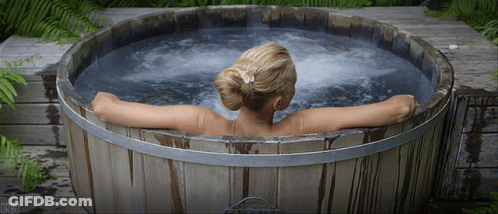 A Woman Is Sitting In A Wooden Tub With The Letters Dr80 On The Bottom GIF