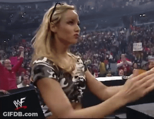 A Woman Is Sitting In A Wrestling Ring With A Wwe Logo On The Back Of Her Shirt . GIF