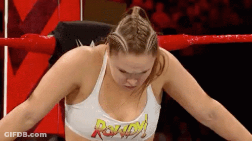 A Woman Is Sitting In A Wrestling Ring With Her Arms Outstretched . GIF