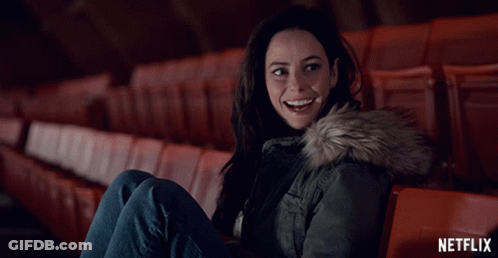 A Woman Is Sitting In An Auditorium With A Netflix Logo In The Background GIF