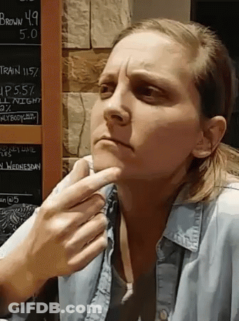 A Woman Is Sitting In Front Of A Chalkboard That Says Brown 4.9 On It GIF
