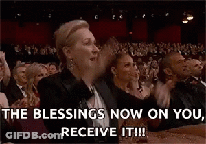 A Woman Is Sitting In Front Of A Crowd With Her Arms In The Air And Says `` The Blessings Now On You Receive It ! '' GIF