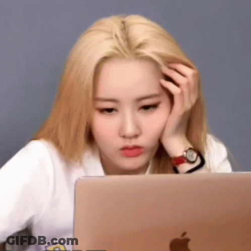 A Woman Is Sitting In Front Of A Laptop Computer With Her Hand On Her Forehead . GIF