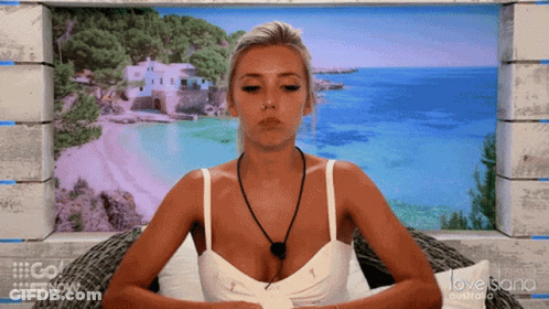 A Woman Is Sitting In Front Of A Love Island Australia Poster GIF