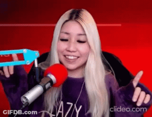 A Woman Is Sitting In Front Of A Microphone And Smiling . GIF