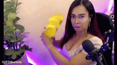 A Woman Is Sitting In Front Of A Microphone Holding A Yellow Object . GIF