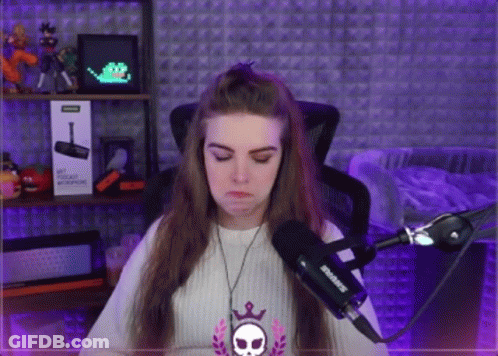 A Woman Is Sitting In Front Of A Microphone With A Skull Necklace Around Her Neck GIF