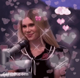 A Woman Is Sitting In Front Of A Microphone With Hearts Around Her Head . GIF