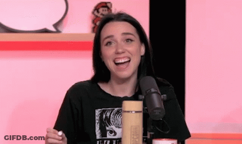 A Woman Is Sitting In Front Of A Microphone With Her Mouth Open And Smiling . GIF
