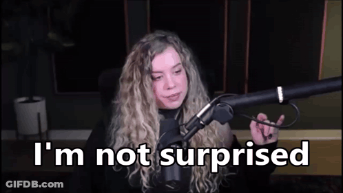A Woman Is Sitting In Front Of A Microphone With The Words `` I 'M Not Surprised '' Written On The Screen . GIF