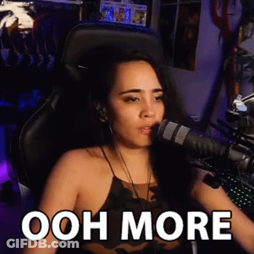A Woman Is Sitting In Front Of A Microphone With The Words Ooh More Written On Her Face . GIF