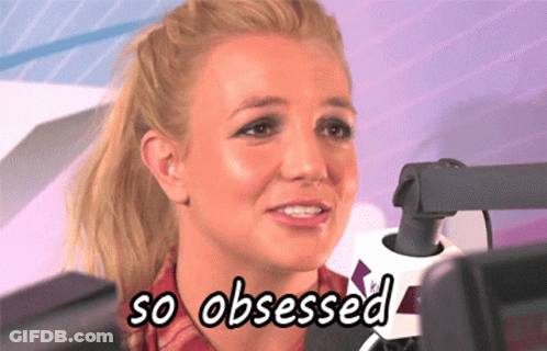 A Woman Is Sitting In Front Of A Microphone With The Words So Obsessed Below Her GIF