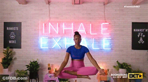 A Woman Is Sitting In Front Of A Neon Sign That Says Inhale Exhale GIF